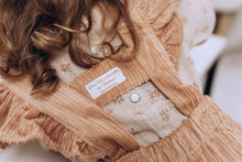 Charger l'image dans la galerie, Blouse bébé fille Flora en double gaze de coton lin beige à fleurs corail et jupe à bretelles volantées en velours côtelé vieux rose durable et écoresponsable fabriquées en France par Les p'tites Merveilles de Bérénice portées par Charlie 24 mois