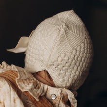 Charger l'image dans la galerie, Bonnet béguin bébé mixte tricoté en laine mérinos mélangée écru avec nœud style bohème rétro vintage pour Les p'tites Merveilles de Bérénice porté par Lison 6 mois