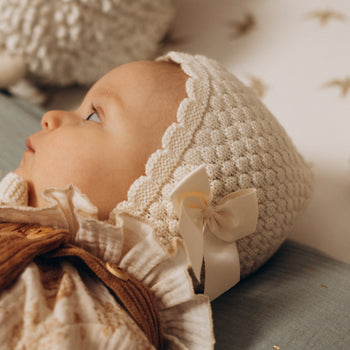Bonnet béguin bébé mixte tricoté en laine mérinos mélangée écru avec nœud style bohème rétro vintage pour Les p'tites Merveilles de Bérénice porté par Lison 6 mois